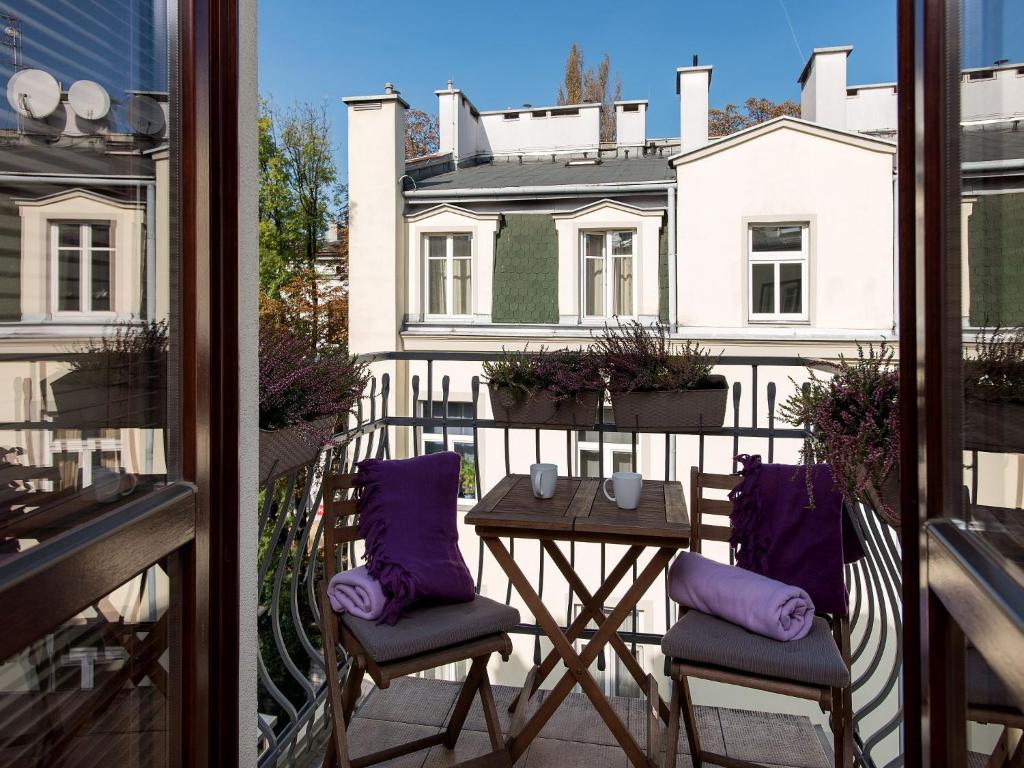 Un balcón con 2 sillas y una mesa con almohadas moradas. en Lucky 13, en Cracovia