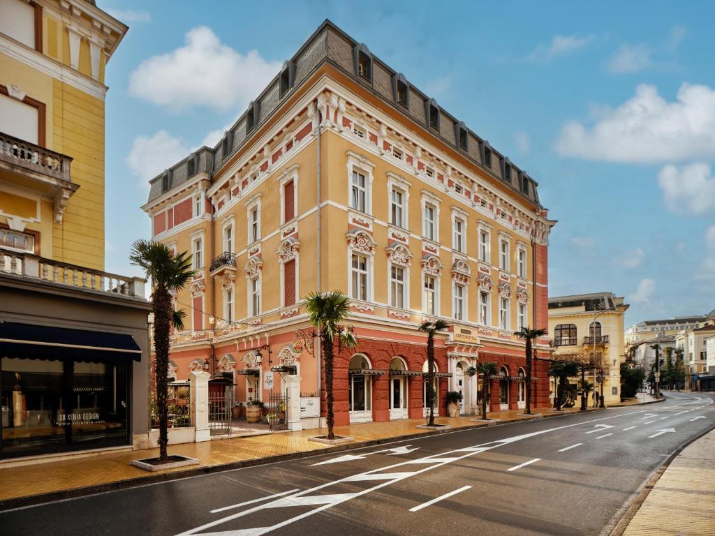 a large building on a street with palm trees at Hotel Continental in Opatija