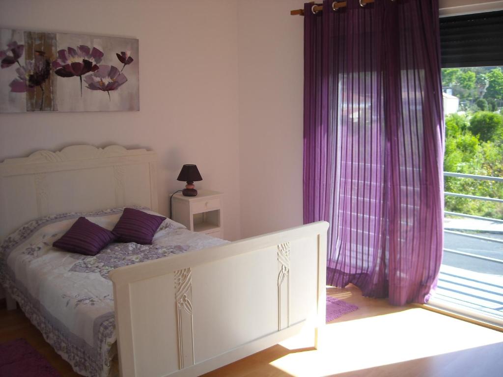 ポンタ・デルガダにあるSweet Dreams ALのベッドルーム1室(紫色のカーテンと窓付きのベッド1台付)