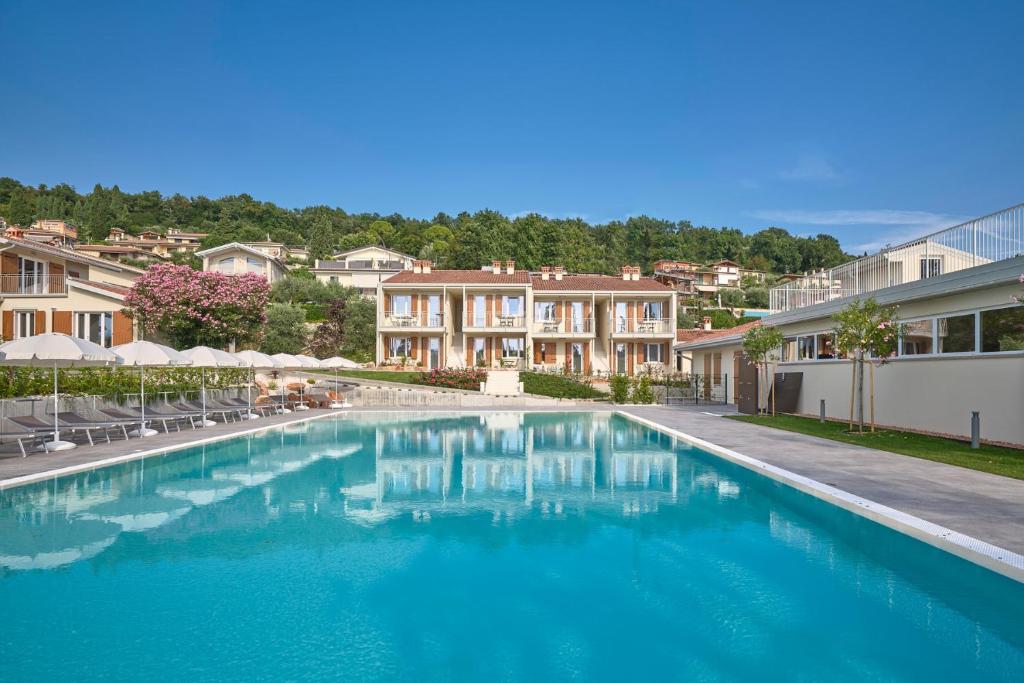 a swimming pool with blue water in front of houses at Residence Green Park in Torri del Benaco