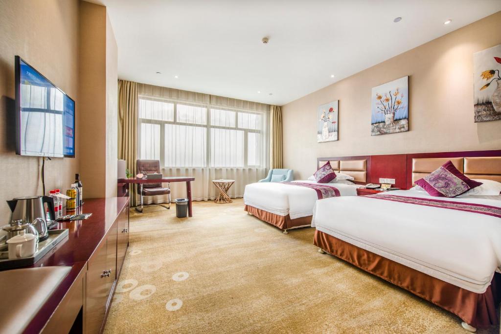 ein Hotelzimmer mit zwei Betten und einem Fernseher in der Unterkunft Minghua Hotel in Wen-su-lao-ch'eng