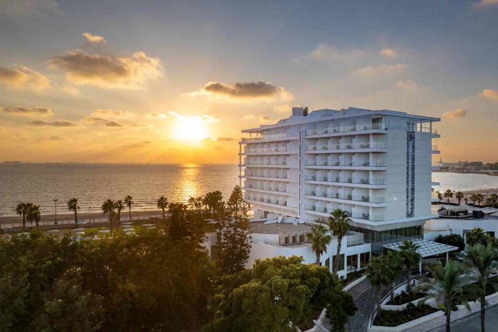 Blick auf ein Hotel und das Meer bei Sonnenuntergang in der Unterkunft Palm Beach Hotel - Mehadrin Kosher suitable for Ultra-Orthodox guests in Akkon