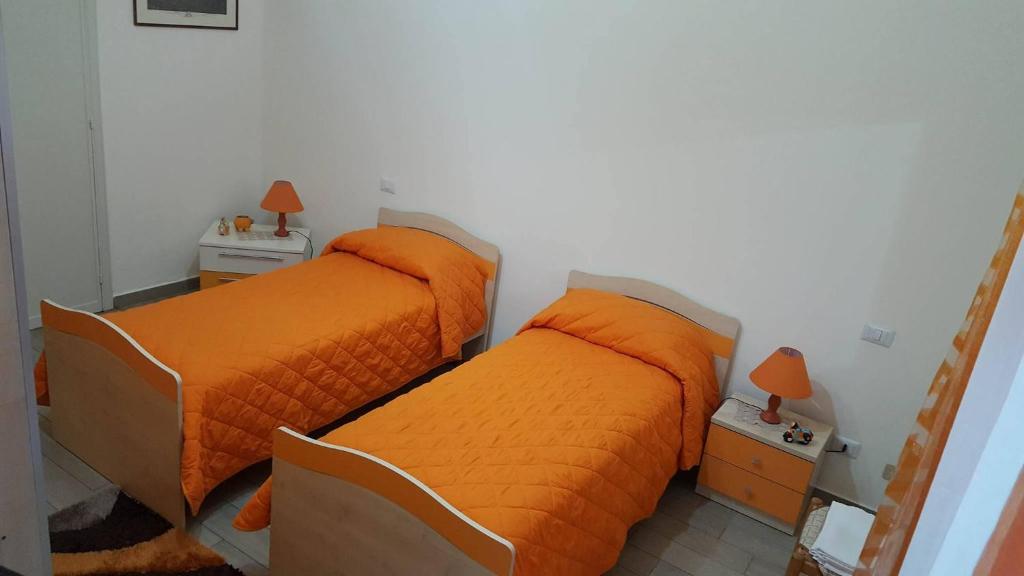 2 letti in una camera da letto con lenzuola arancioni di B&b Irma a Olivarella