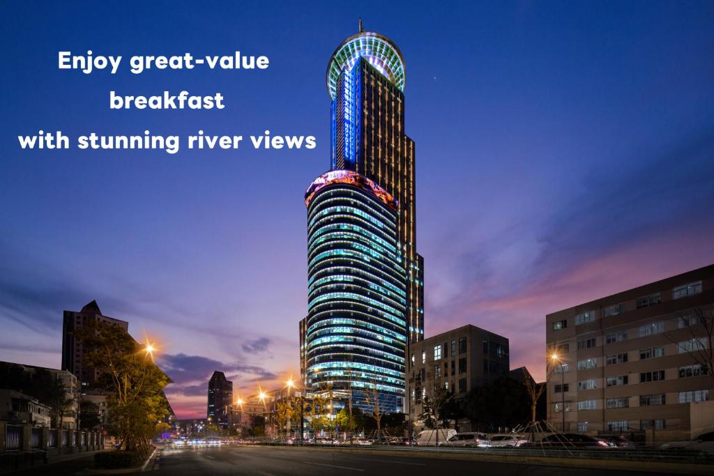 a tall building is lit up at night at Novotel Atlantis Shanghai in Shanghai