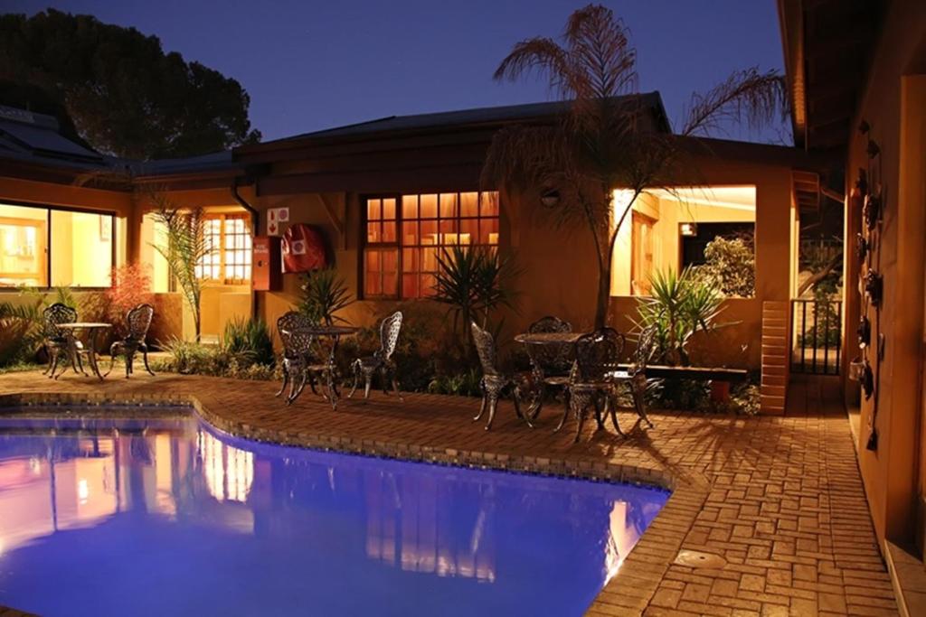 a house with a swimming pool with tables and chairs at Greenleaf Guest Lodge in Bloemfontein