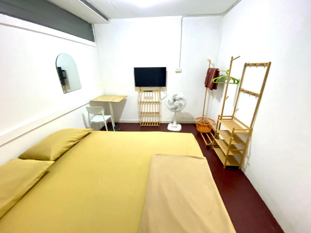 a bedroom with a yellow bed and a television at J&T House And Friends in Ban Khlong Nam Ron