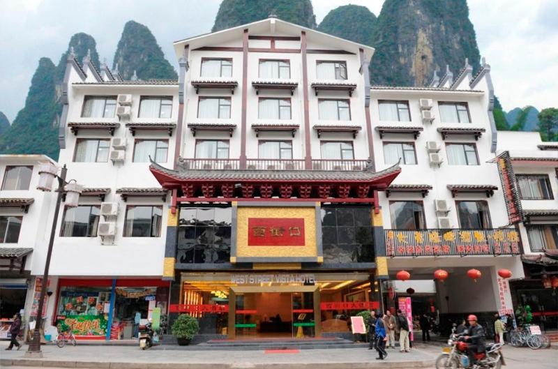 a large building with people walking in front of it at West Street Vista Hotel in Yangshuo