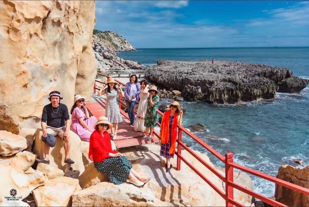 a group of people standing on the steps to the beach at HOTEL vùng vịnh in Cầu Sông Kinh