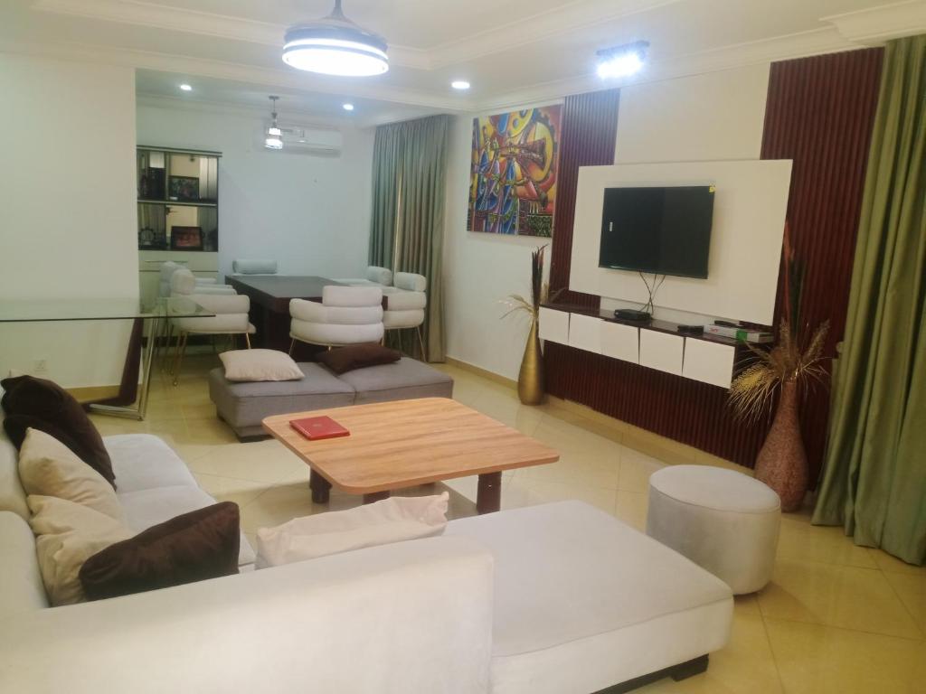 a living room with a white couch and a tv at Pine smart apartment Apo in Abuja