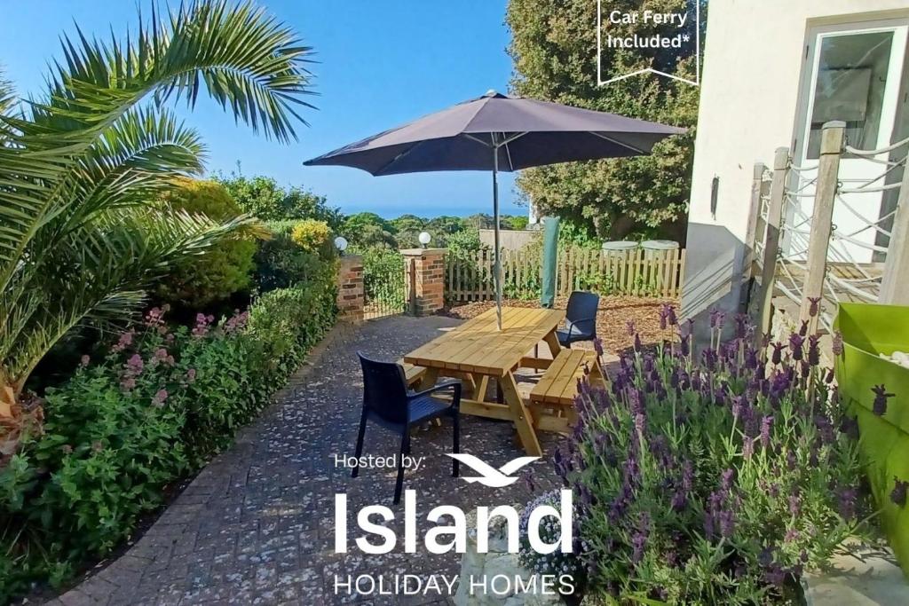 a table and chairs with an umbrella in a garden at Sea Grove in Ventnor