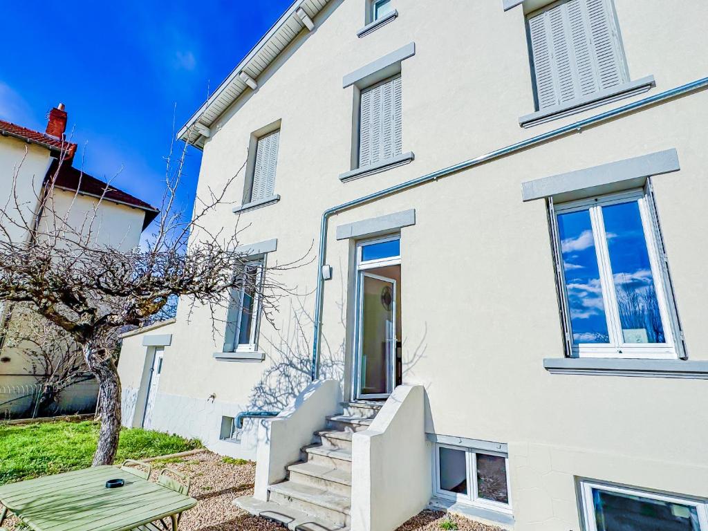 a white house with stairs and a tree at Grand appartement avec jacuzzi et jardin in Clermont-Ferrand