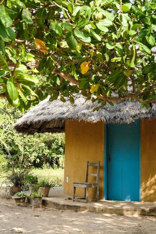 a chair sitting outside of a hut with a blue door at Campement Outouka in Kafountine