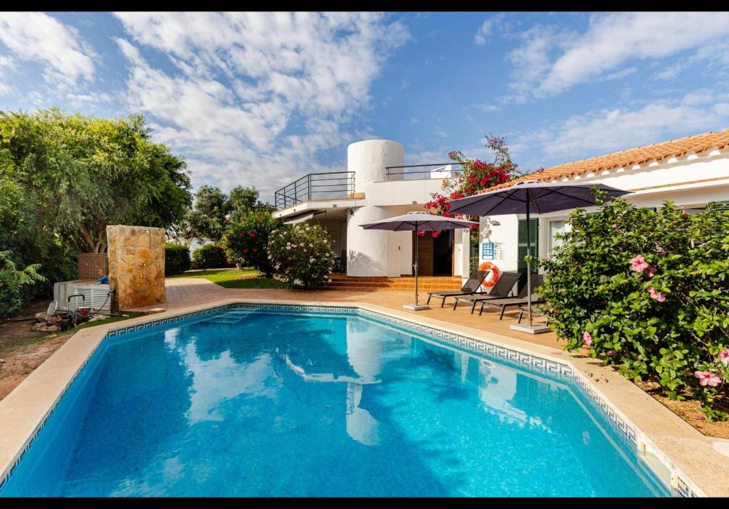 a swimming pool in front of a house at Villa Adele Binibeca sea view in Binibeca