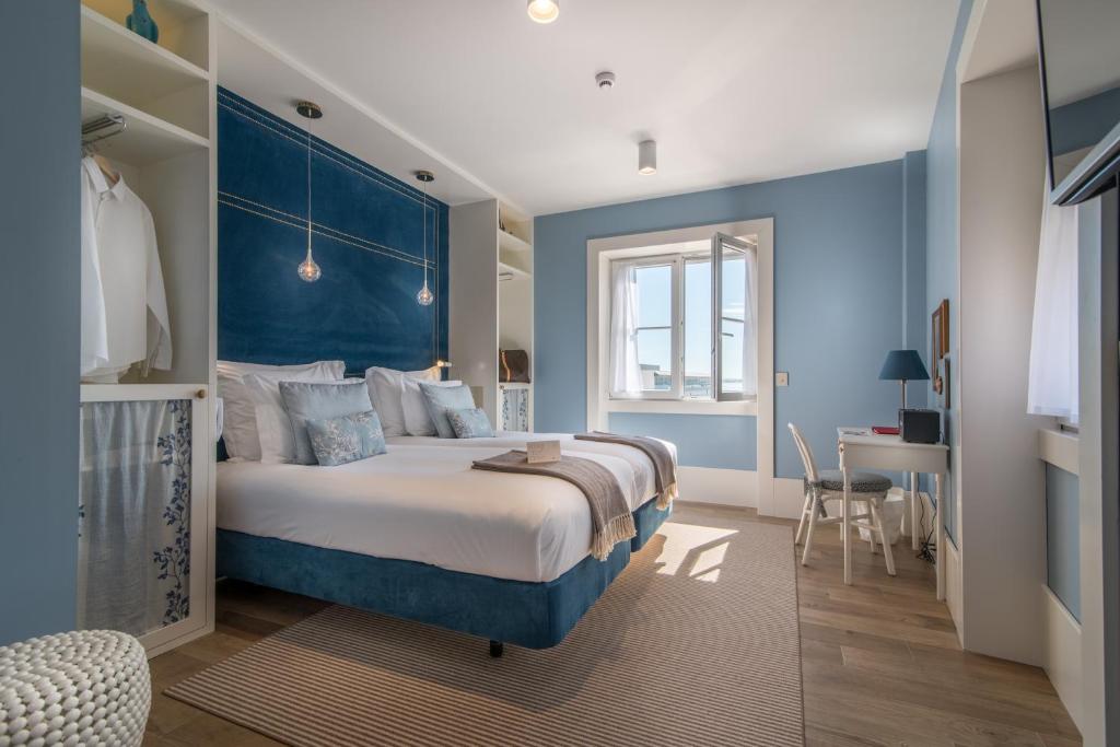 een slaapkamer met een groot bed met een blauw hoofdeinde bij Lx Boutique Hotel in Lissabon