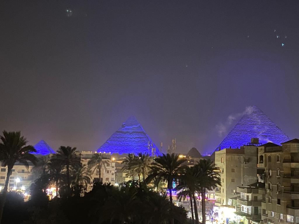 two pyramids are lit up in blue at night at Crown pyramids hotel in Cairo