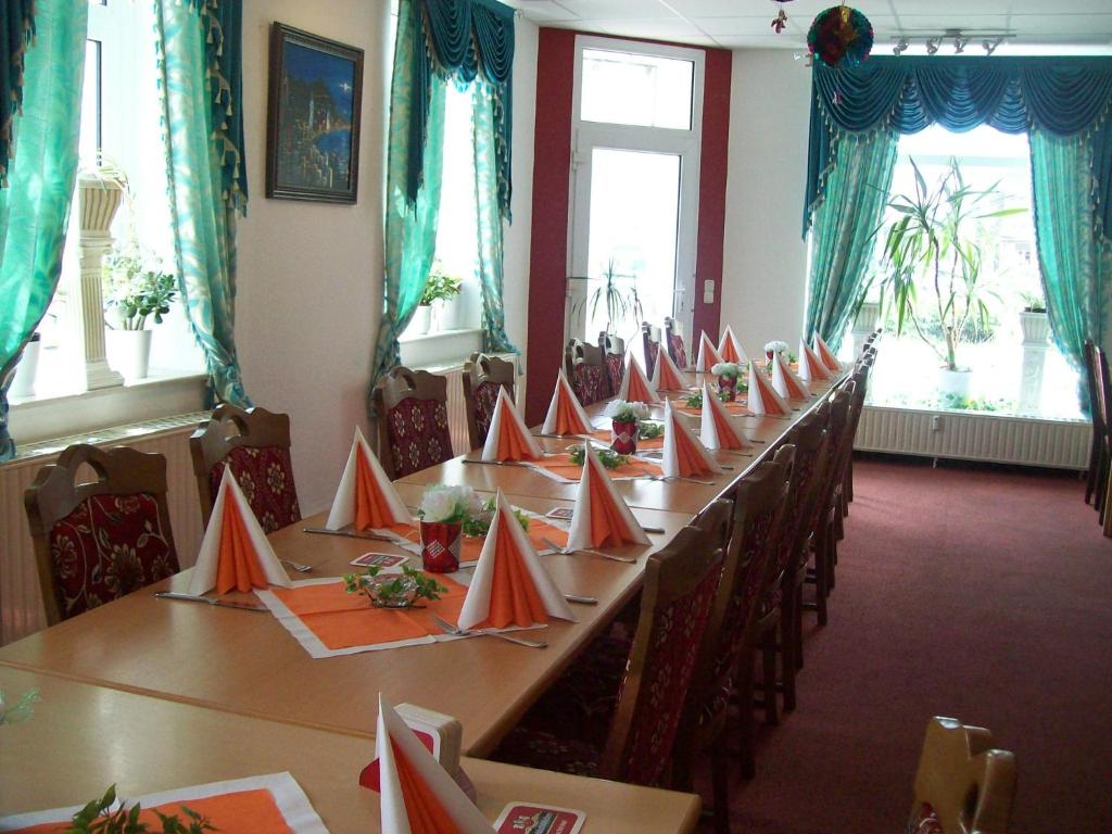a room with a long table with red paper cones on it at Hotel Restaurant Rhodos in Elsterwerda