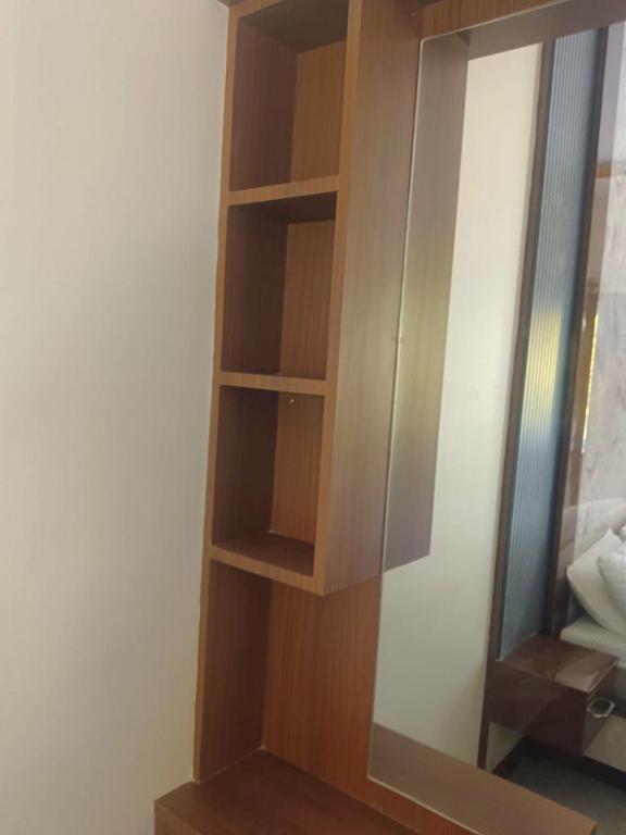 a wooden book shelf next to a mirror at Dreamscape Rooms - Yelagiri in Yelagiri