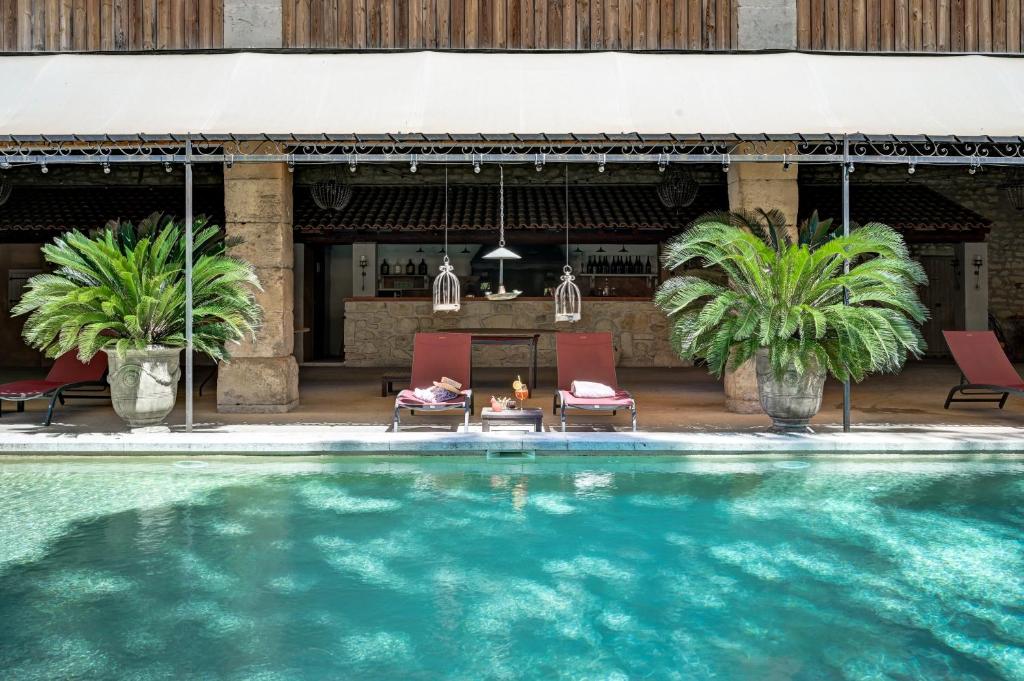a woman sitting in chairs by a swimming pool at Mas des Comtes de Provence in Tarascon