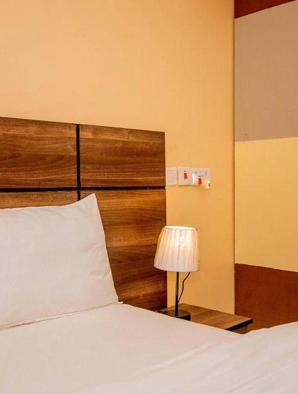 a bedroom with a bed with a wooden headboard and a lamp at River point inn in Arusha
