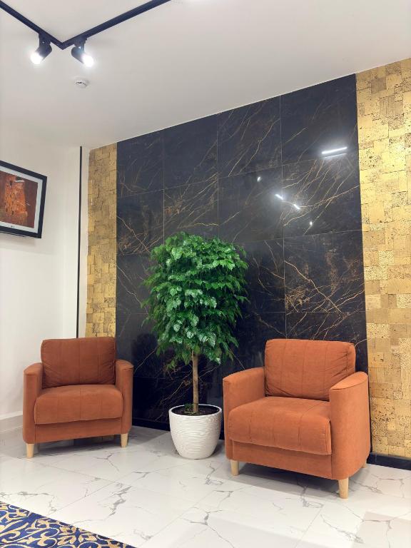 two chairs and a potted plant in a lobby at Avenue Hotel in Almaty