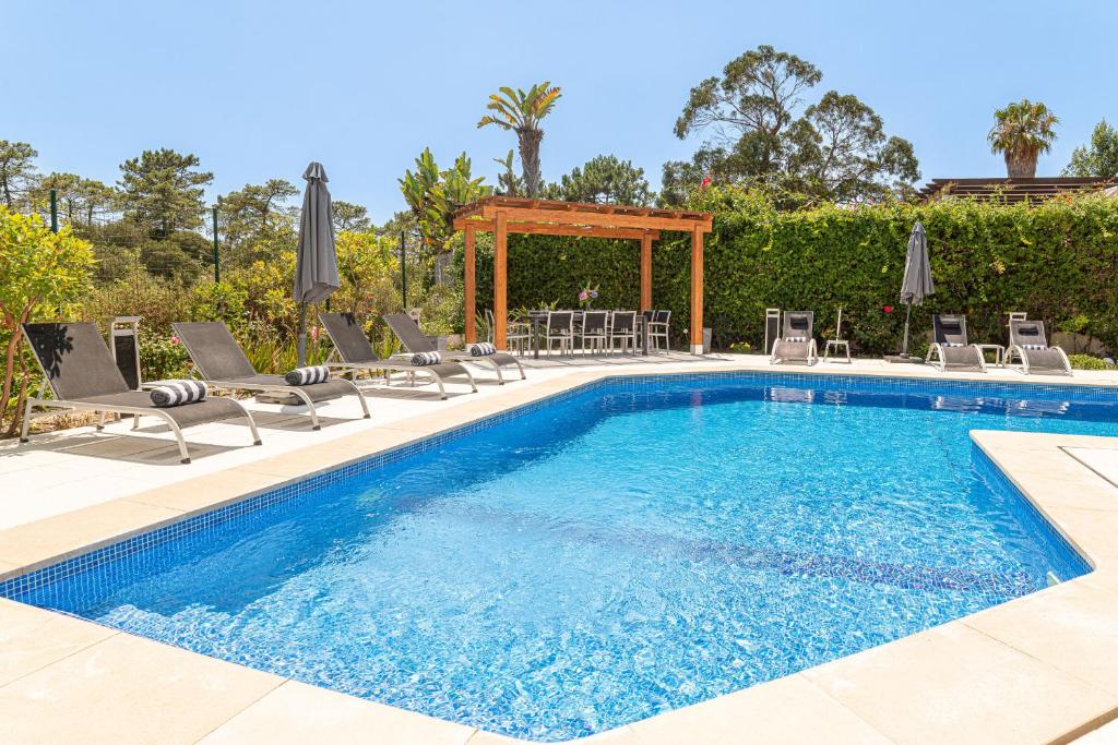 a swimming pool with chairs and a gazebo at Villa Atlantica in Setúbal