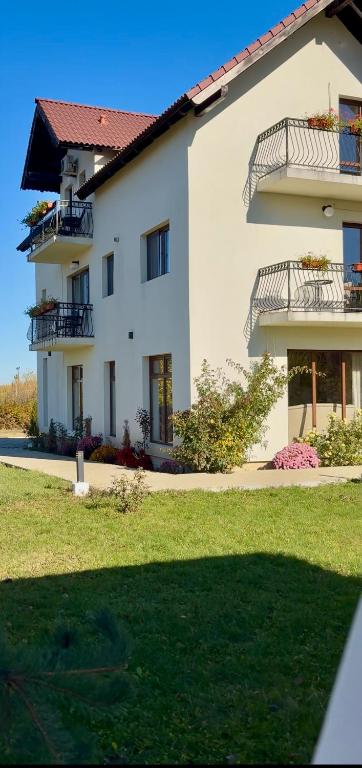 a large white building with balconies and a yard at Pensiunea Ivoire in Avrig