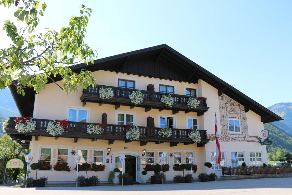 un grand bâtiment blanc avec un toit noir dans l'établissement Gasthof Weissenbach, à Strobl