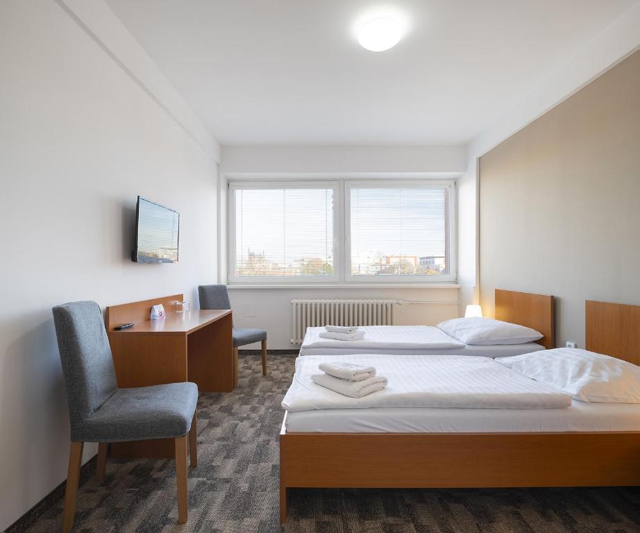 a room with two beds and a desk and a chair at Hotel Veronika in Ostrava
