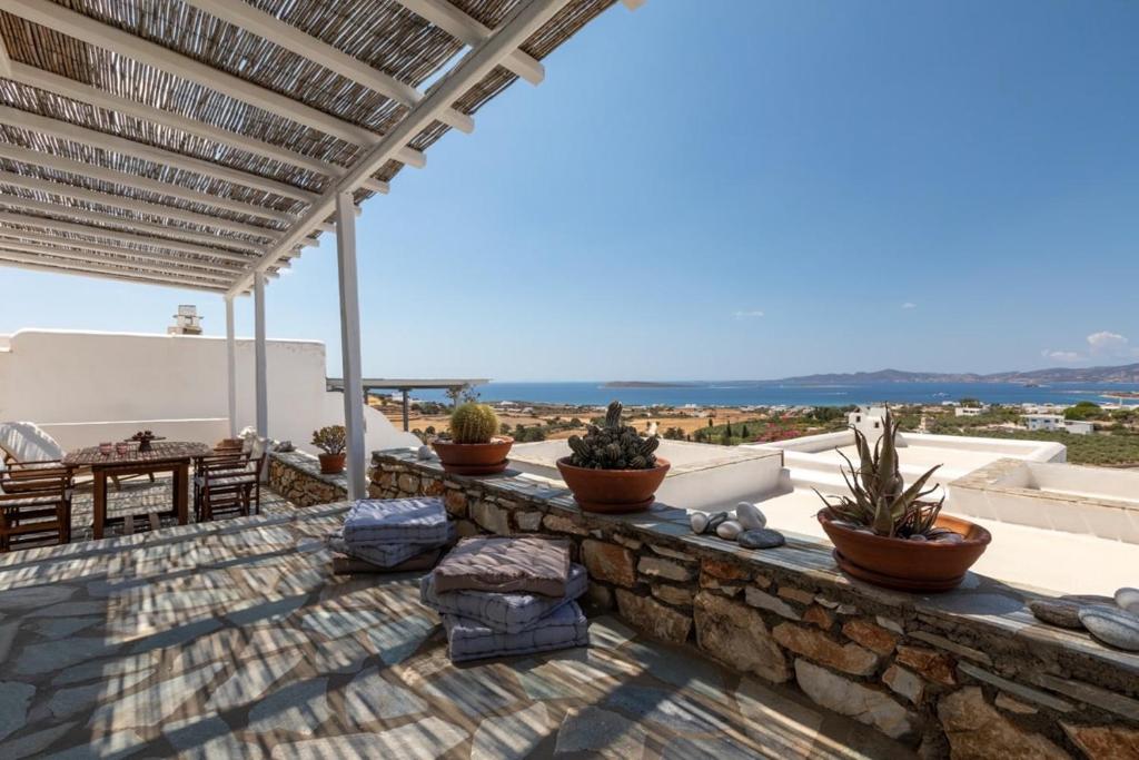 a patio with potted plants on a stone wall at Big Blue Sunset View in Angairiá