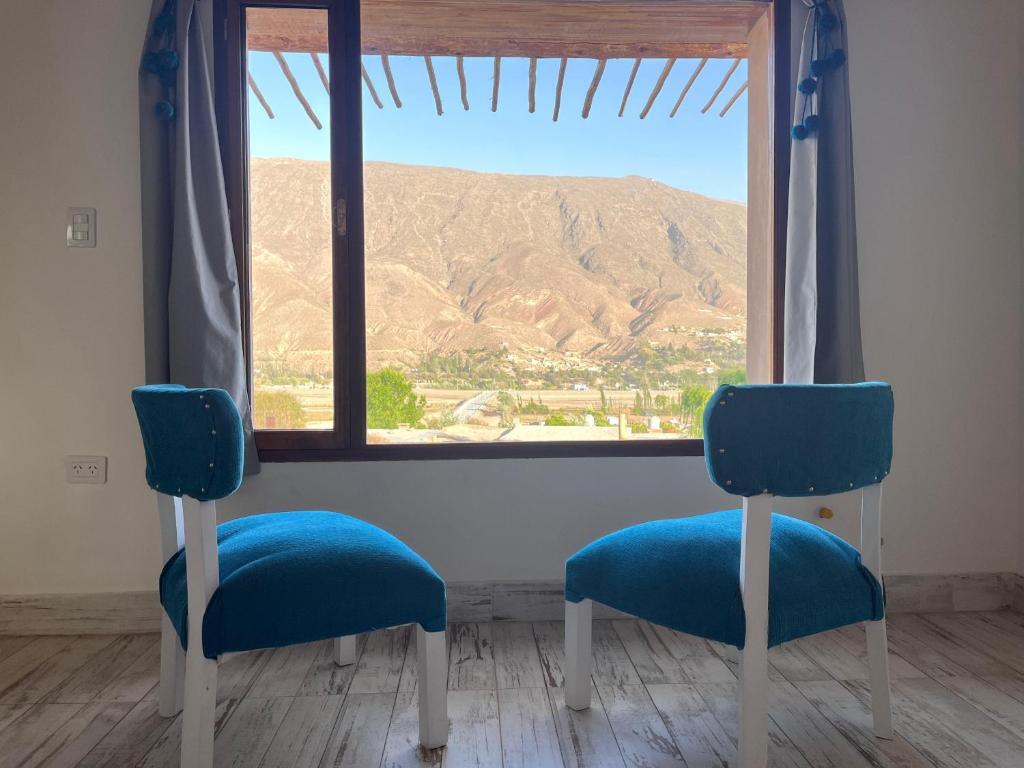two blue chairs sitting in front of a window at Posada Suri Huasi in Tilcara