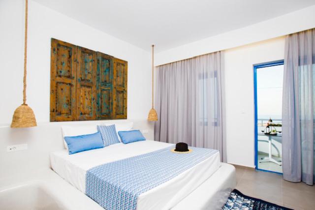 a white bedroom with a bed and a large window at Lindos Portes Blue in Lindos
