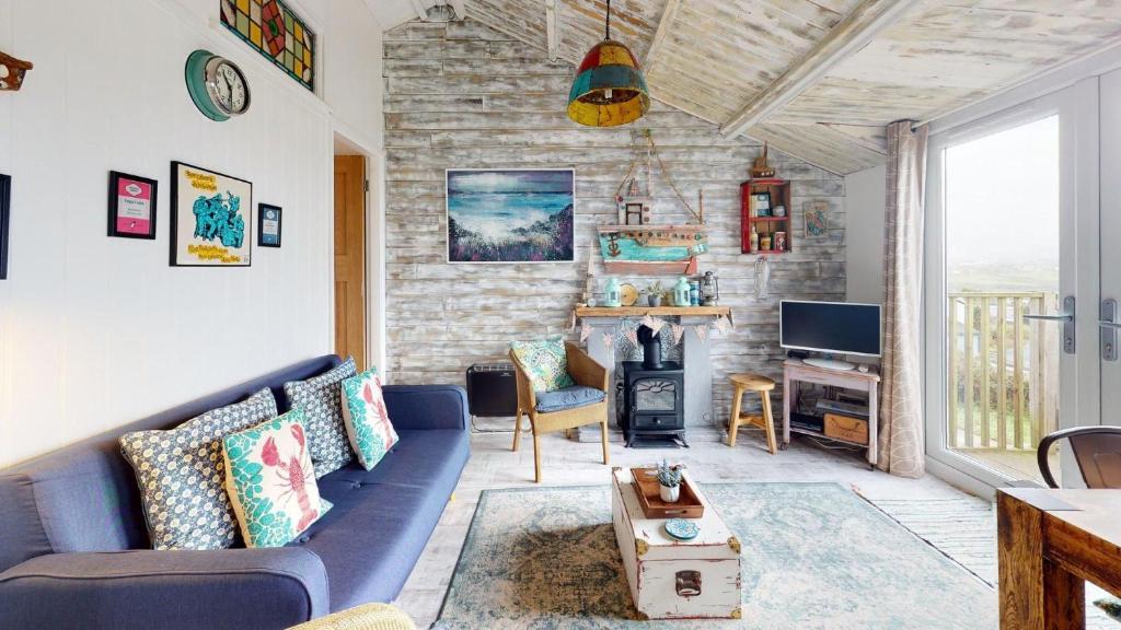 a living room with a blue couch and a fireplace at E41 Silver Mist, Riviere Towans in Hayle