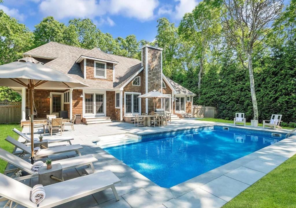 a house with a swimming pool with chairs and umbrellas at Villa Montauk Mist in East Hampton