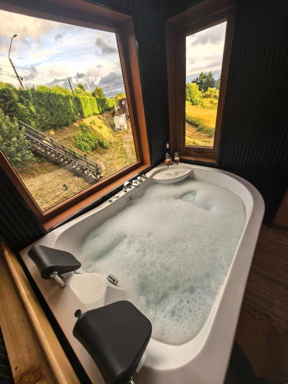 a bath tub in a bathroom with two windows at Loft Wilef in Tentén
