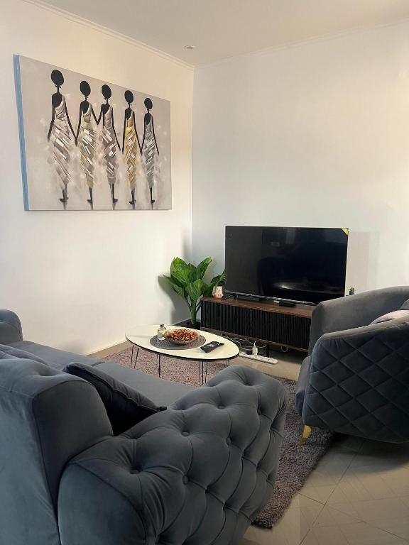 a living room with a couch and a flat screen tv at Bungo Home - Suite Chambre & salon à 2 min de la plage in Pointe-Noire