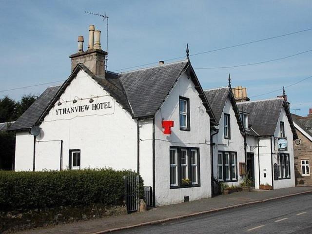 a white building with a sign for a tenneway hotel at Ythanview Hotel in Methlick