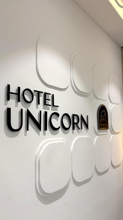 a sign for a hotel unicorn on a wall at Hotel Unicorn Althan, Surat in Surat