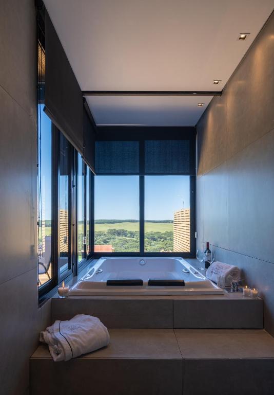 a large bathroom with a large tub with a large window at Cabanas Horizonte Cambará Nature in Cambará