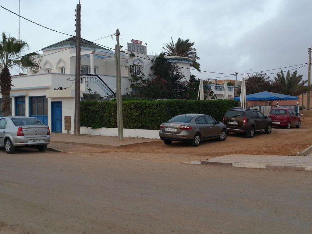 eine Gruppe von Autos, die an der Straßenseite geparkt sind in der Unterkunft Hotel Canarias Sahara in Tan-Tan Plage