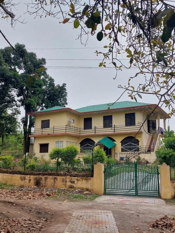 a large yellow house with a fence in front of it at Commander's Home in Kangra