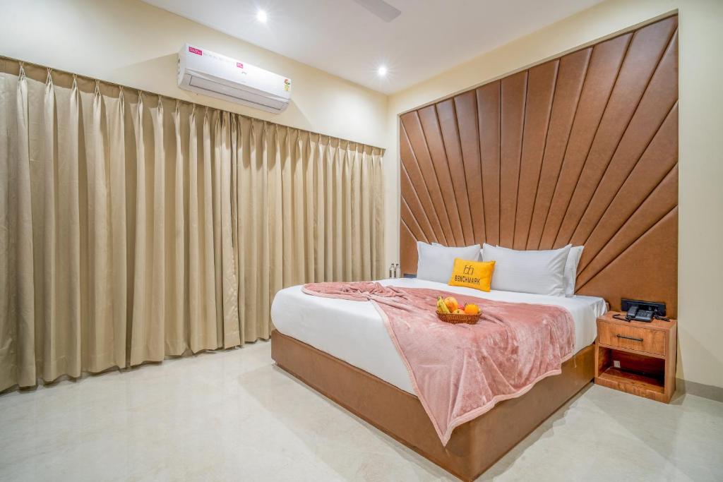 a bedroom with a large bed with a wooden headboard at Benchmark Residences in Indore