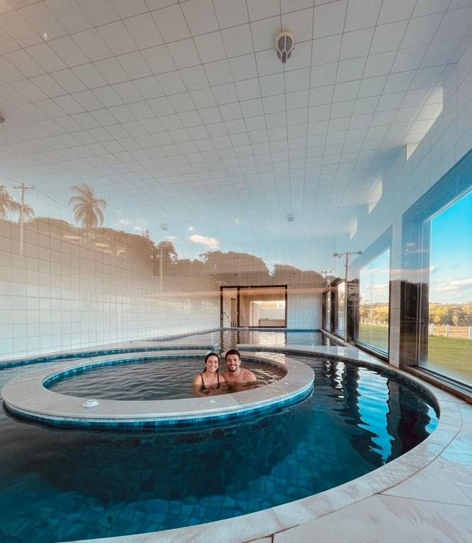 two people in a swimming pool in a building at Lagamar Hotel Varginha in Varginha