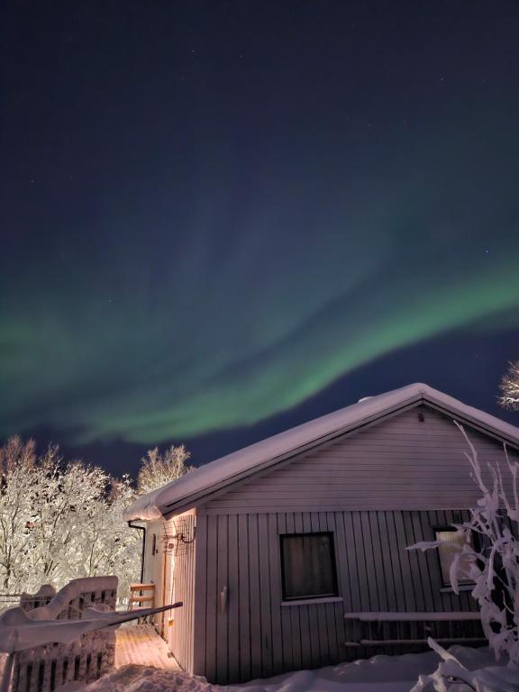 an image of the aurora borealis over a cabin at Cozy House in Tromsø - Near City Center, Ideal for Families & Groups in Tromsø