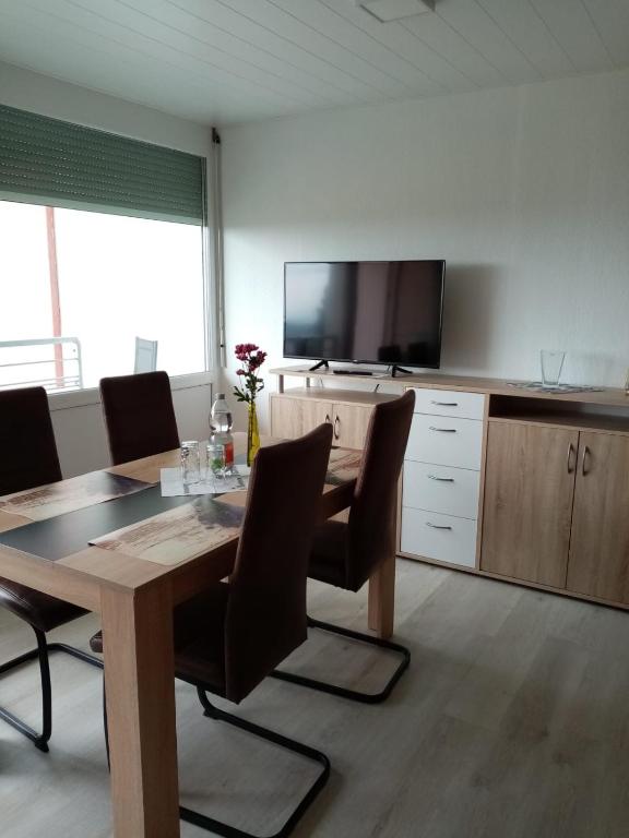 a dining room with a table and a flat screen tv at Schönes, modernes Appartement mit Balkon und Indoorpool in Oberteuringen