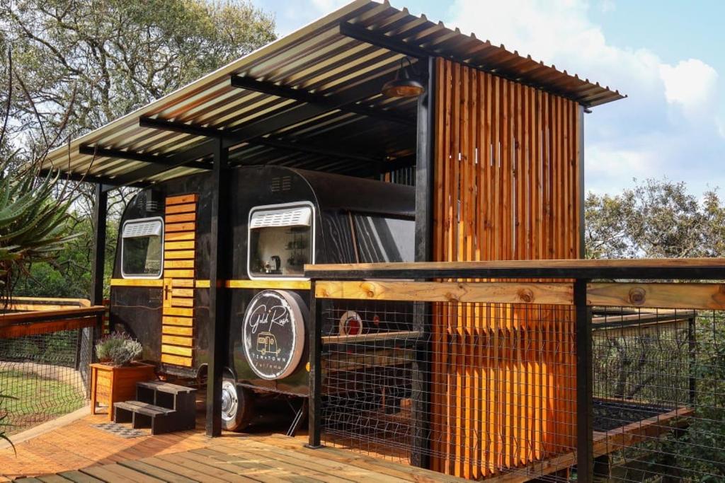 an old bus is sitting under a shed at Tin Town Glamping in Haenertsburg
