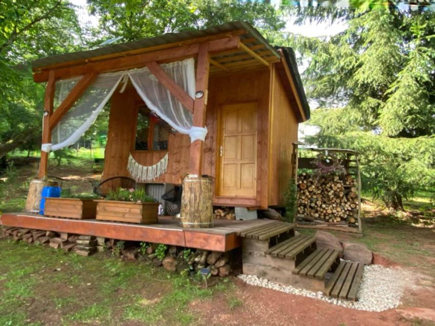a small wooden cabin with a porch and a fence at Tiny Resort Chotěvice 1 in Chotěvice