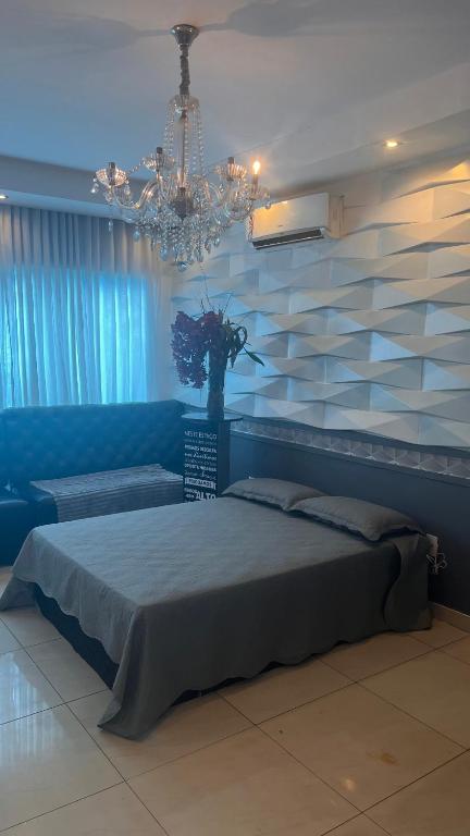 a bedroom with a large bed and a chandelier at Flat Luz in Guarabira