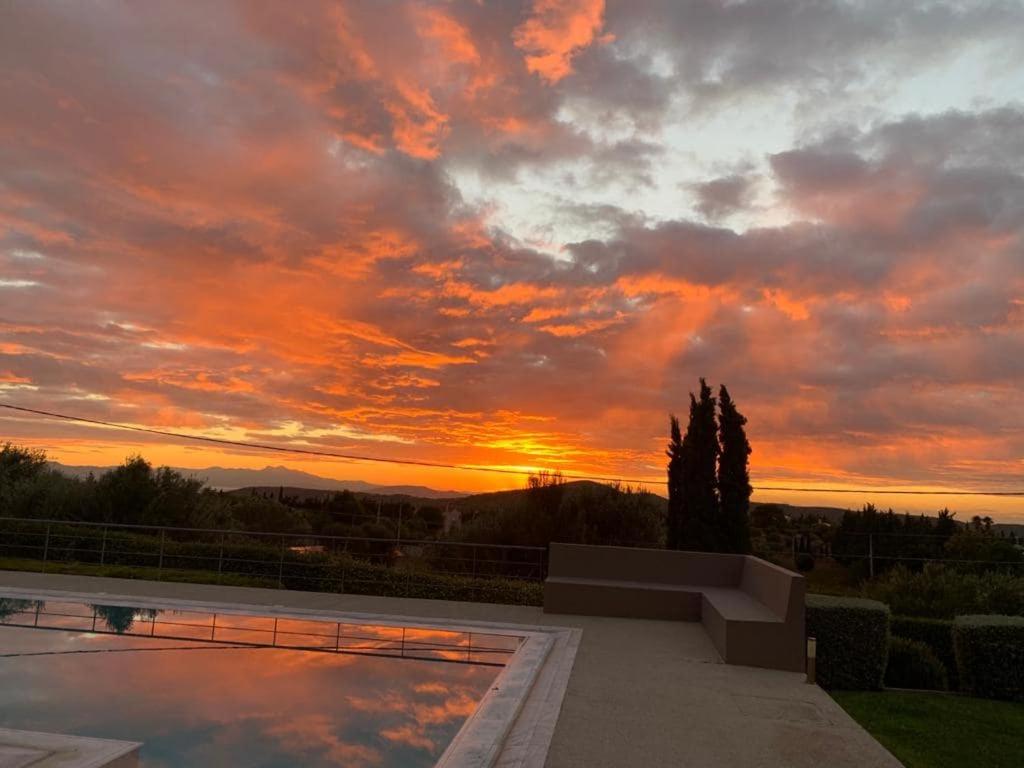 a sunset over a swimming pool with the sky at Pikermi garden suite in Pikérmion