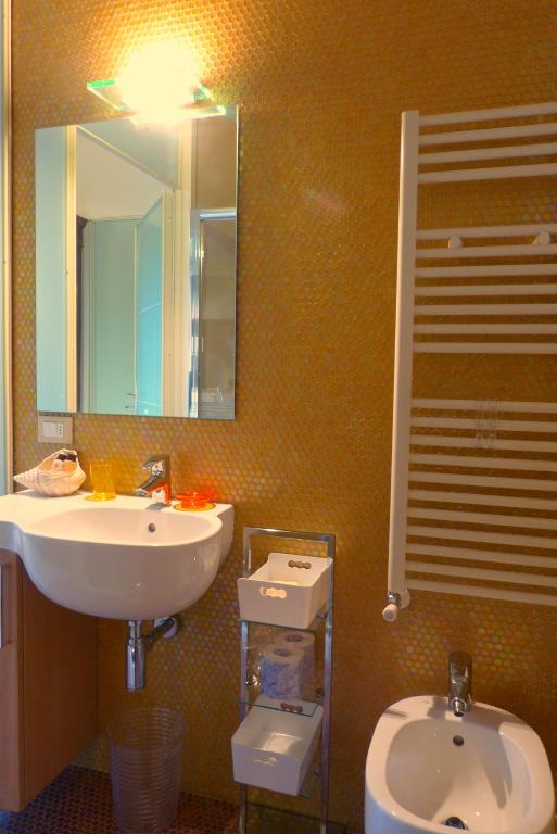 łazienka z umywalką, toaletą i lustrem w obiekcie Relais Pacinotti Apartments w Pizie