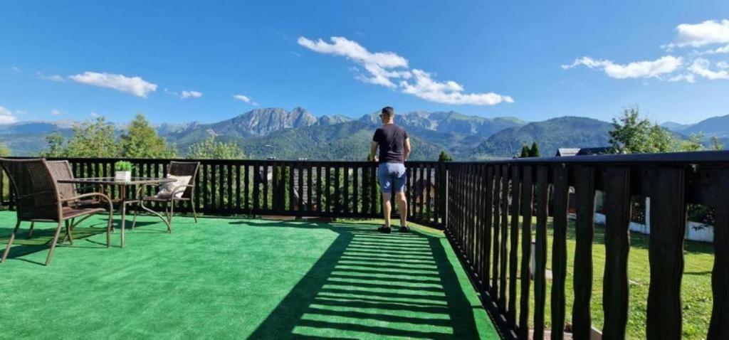 a man standing on a deck looking at the mountains at Apartamenty Butorówka Dream 100m2 , Kościelisko - Zakopane in Kościelisko